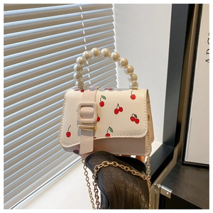 Detail of white PU leather crossbody bag featuring cherry print and pearl beaded handle