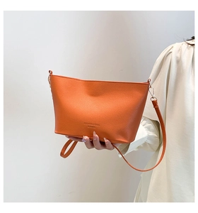 Détail du sac seau en cuir orange avec grain de litchi et logo embossé élégant