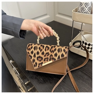 Detail of leopard print shoulder bag with golden twist handle and adjustable strap