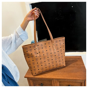 Detailed view of brown bear monogram pattern and gold rivets on the leather tote bag