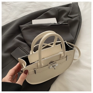 Vue détaillée d'un sac demi-lune en cuir crème avec fermoir argenté sur une veste