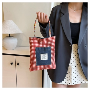 Détail d'un cabas à carreaux rouges et blancs avec poche en denim et anses tressées