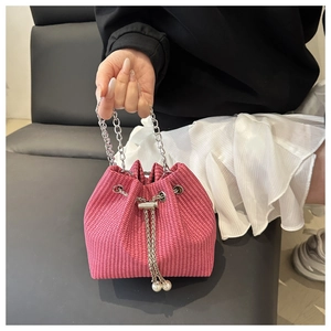 Détail du sac seau rose tressé avec poignée chaîne argentée et détails en perles blanches