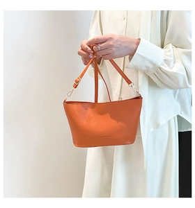 Détail du sac cabas en cuir grainé orange avec boucle dorée et logo embossé sur le devant