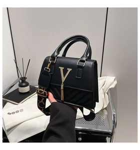 Detail of black PU leather crossbody bag with golden V logo and quilted pattern