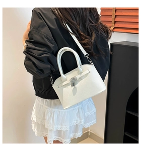 Vista posteriore di una modella con borsa a tracolla in pelle bianca grana litchi e lucchetto