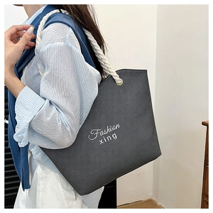 Detail of black tote bag with white rope handles and Fashion xing artistic lettering