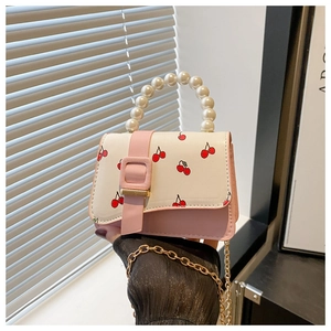 Detail of pink and white crossbody bag with cherry print and pearl beaded handle