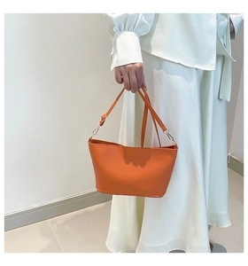 Détail du sac seau orange avec texture litchi de qualité et fermoirs en métal doré brillant