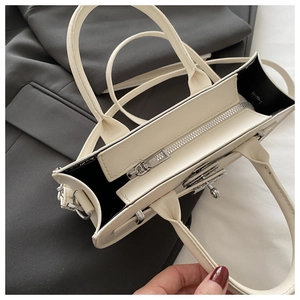 Détail de la fermeture éclair argentée et de la boucle rotative sur le sac blanc