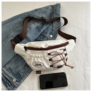 Detail of cream canvas crossbody bag featuring brown drawstring pocket and leather label