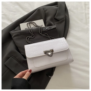 Detail of white crocodile embossed crossbody bag with black metal chain on grey blazer