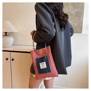 Détail du sac cabas à carreaux rouges avec poche en denim et anse en perles colorées