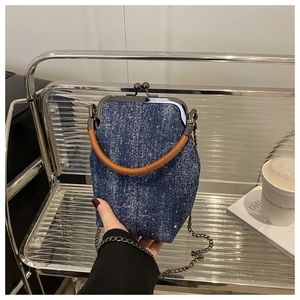 Détail du sac bandoulière en denim avec poignée en cuir, chaîne et fermoir vintage
