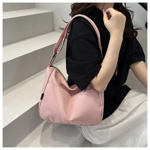 Detail of pink nylon crossbody bag featuring V-shaped pleats and adjustable shoulder strap