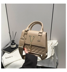 Detail of beige quilted leather handbag with gold V-logo, metal tassel and stylish strap