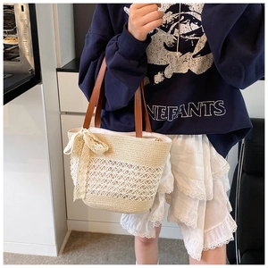 Close-up of woven straw tote with hollow mesh pattern and white lace bow detail