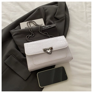 Detailed macro view of white crocodile pattern PU leather with metal chain and lock