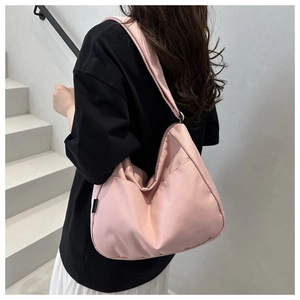 Pink crescent hobo bag for women worn by a model against a minimalist white stairs background