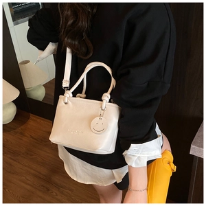 Detail of white PU leather handbag with embossed lettering and smile charm on a model