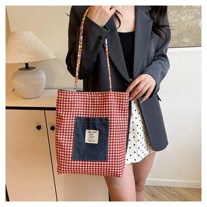 Détail du sac en toile à carreaux rouges avec poche en jean et poignées en corde tressée