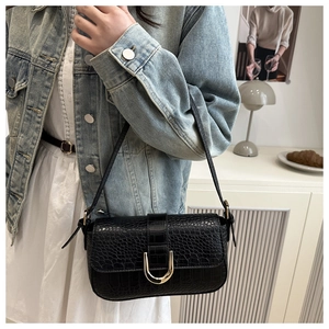 Detail of a black faux crocodile shoulder bag featuring a gold U-shaped metal buckle clasp