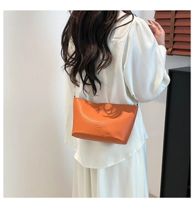 Détail du sac seau orange grainé avec bandoulière en chaîne porté sur vêtement blanc