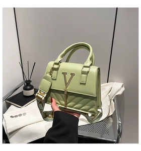 Close-up of light green crossbody bag featuring gold V-clasp and quilted texture detail