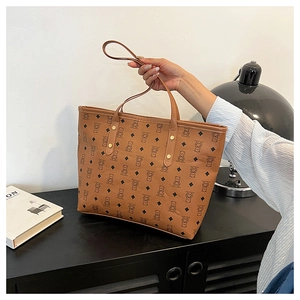 Detail view of large brown tote bag with cute bear pattern and golden rivet handles
