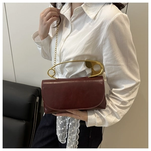 Dettaglio borsa in pelle PU bordeaux con manico a forma di spilla da balia dorata