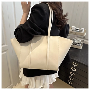 Detailed close-up of a large beige tote bag featuring fashion embossed letters on PU leather