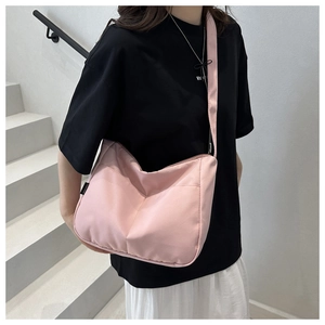 Detailed side view of a pink nylon crossbody tote bag with a minimalist black woven tag