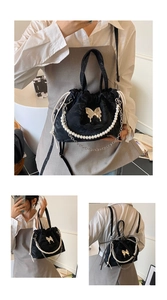 Detailed view of black pleated drawstring bag with gold butterfly clasp and pearl chain