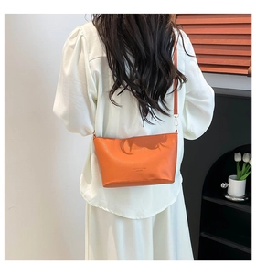 Gros plan du sac seau orange à motif litchi avec détails dorés et bandoulière cuir