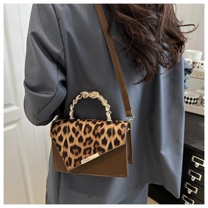 Detail of leopard print flap bag with gold metal handle worn over the shoulder