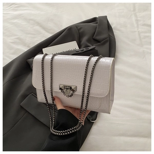 Macro shot of white crocodile embossed texture and vintage metal lock on the bag