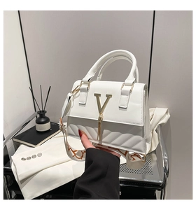 Detail of white quilted leather handbag featuring a gold V logo and orange patterned strap