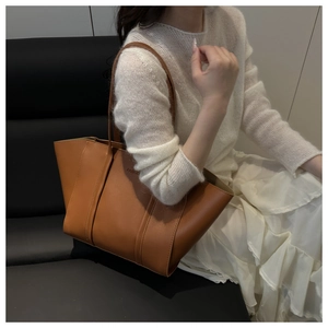 Détail du grand sac cabas en cuir marron avec logo FASHION porté par un mannequin