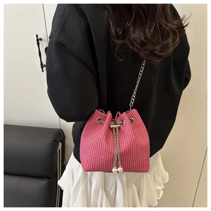 Détail d'un sac seau rose tressé avec cordon à perles et bandoulière chaîne argent