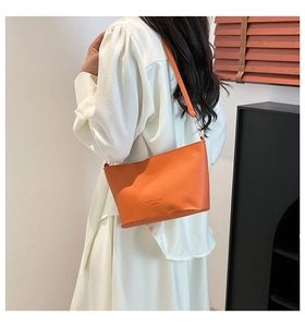 Détail du sac à bandoulière en cuir litchi orange avec texte embossé et texture fine