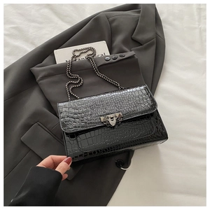 Macro view of black croc-embossed leather finish with metallic stud buckle and chain strap