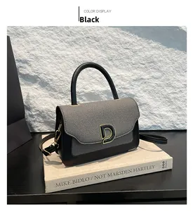 Dettaglio borsa retrò bicolore con fibbia a D dorata esposta sopra dei libri