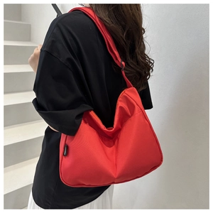 Model wearing a large red nylon hobo bag on a shoulder in a modern urban staircase setting