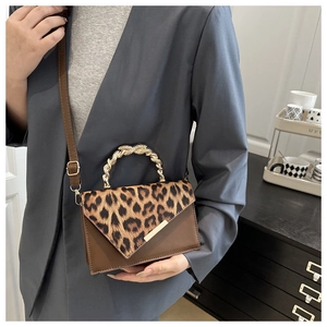 Detail of leopard print flap and twisted gold metal handle on a brown crossbody bag