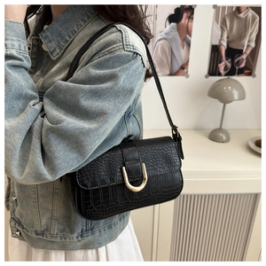 Detail of black crocodile texture bag featuring a decorative gold U-shaped metal buckle