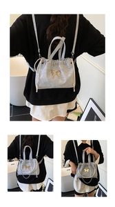 Detail of light blue pleated backpack featuring golden butterfly metal hardware and pearl chain