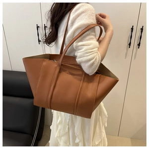 Caramel large tote bag with FASHION lettering and long straps worn by a model