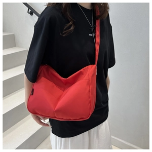 Detail of a bright red canvas crossbody bag with adjustable strap in a casual style