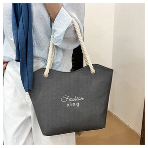 Detail of grey denim tote bag with white cotton rope handles and Fashion xing print