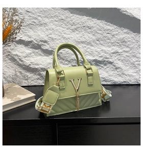 Detail view of mint green textured handbag with V-quilt pattern and gold metal logo charm